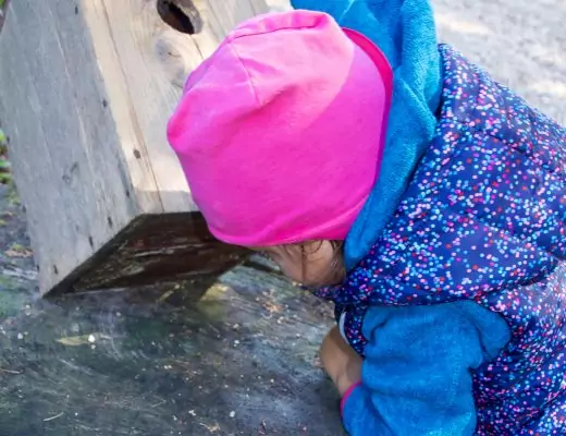 Kind mit dünner Baumwollmütze beim Spielen im Waldkindergarten