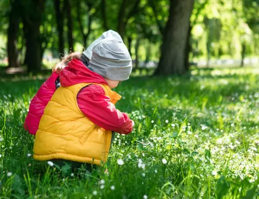 Kind im Waldkindergarten mit Rucksack und Matschkleidung im Frühling