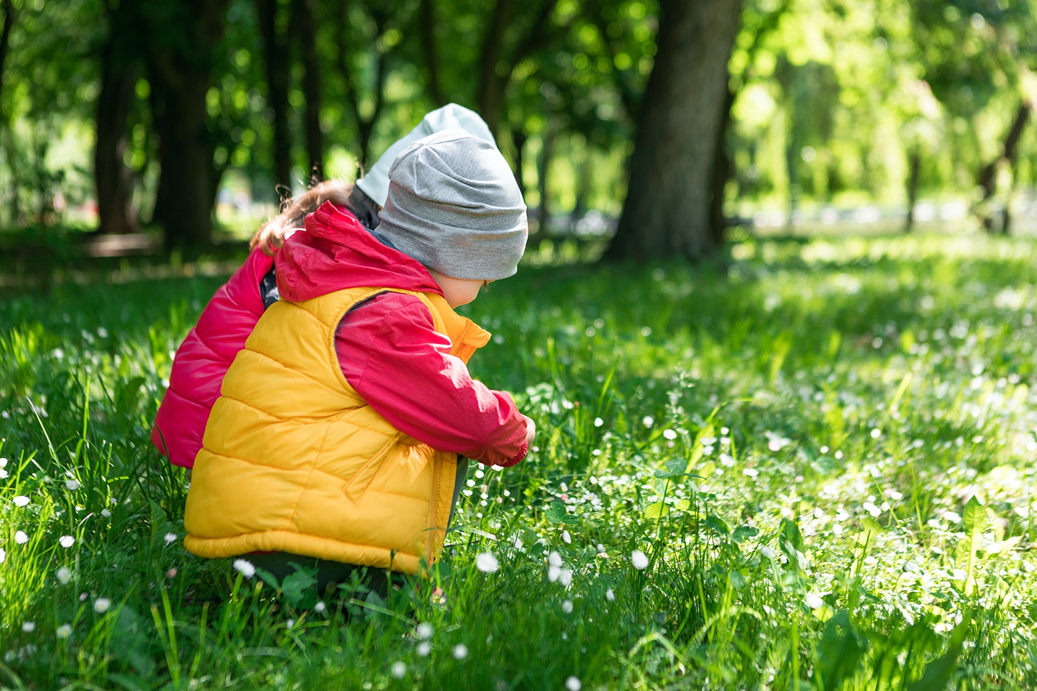 Kind im Waldkindergarten mit Rucksack und Matschkleidung im Frühling
